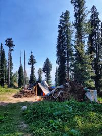 Wooden house on field by trees against sky