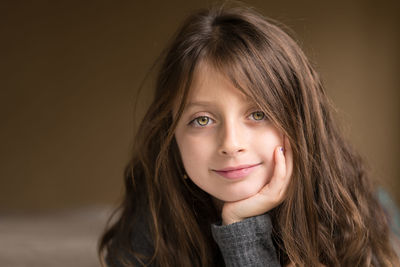 Portrait of smiling girl with hand on chin at home