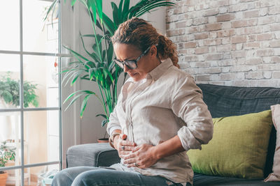 Young woman using laptop while sitting on sofa at home