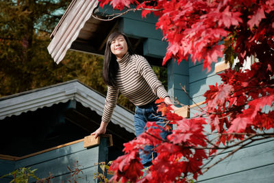 Low angle view of woman standing against house