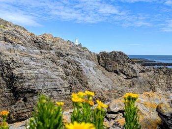 Scenic view of lighthouse, sea and rocks against sky