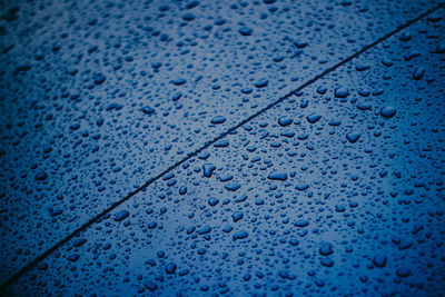 Full frame shot of raindrops on blue glass