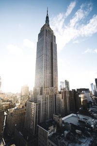 Low angle view of skyscrapers against cloudy sky