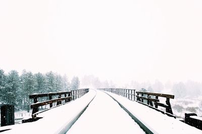 Snow covered railing against clear sky