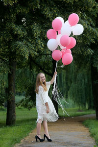 Rear view of woman with balloons against trees
