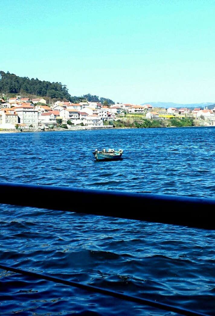 water, clear sky, blue, rippled, waterfront, sea, copy space, built structure, nautical vessel, transportation, architecture, building exterior, river, boat, nature, pier, day, mode of transport, scenics