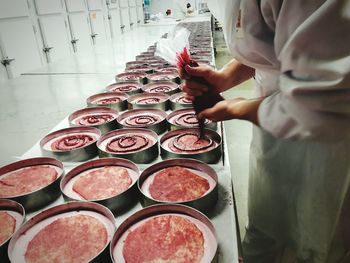 Midsection of chef preparing cakes in kitchen