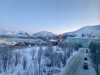 Snow covered buildings by mountain against sky