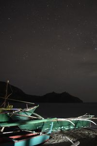 Boats moored in sea against sky at night