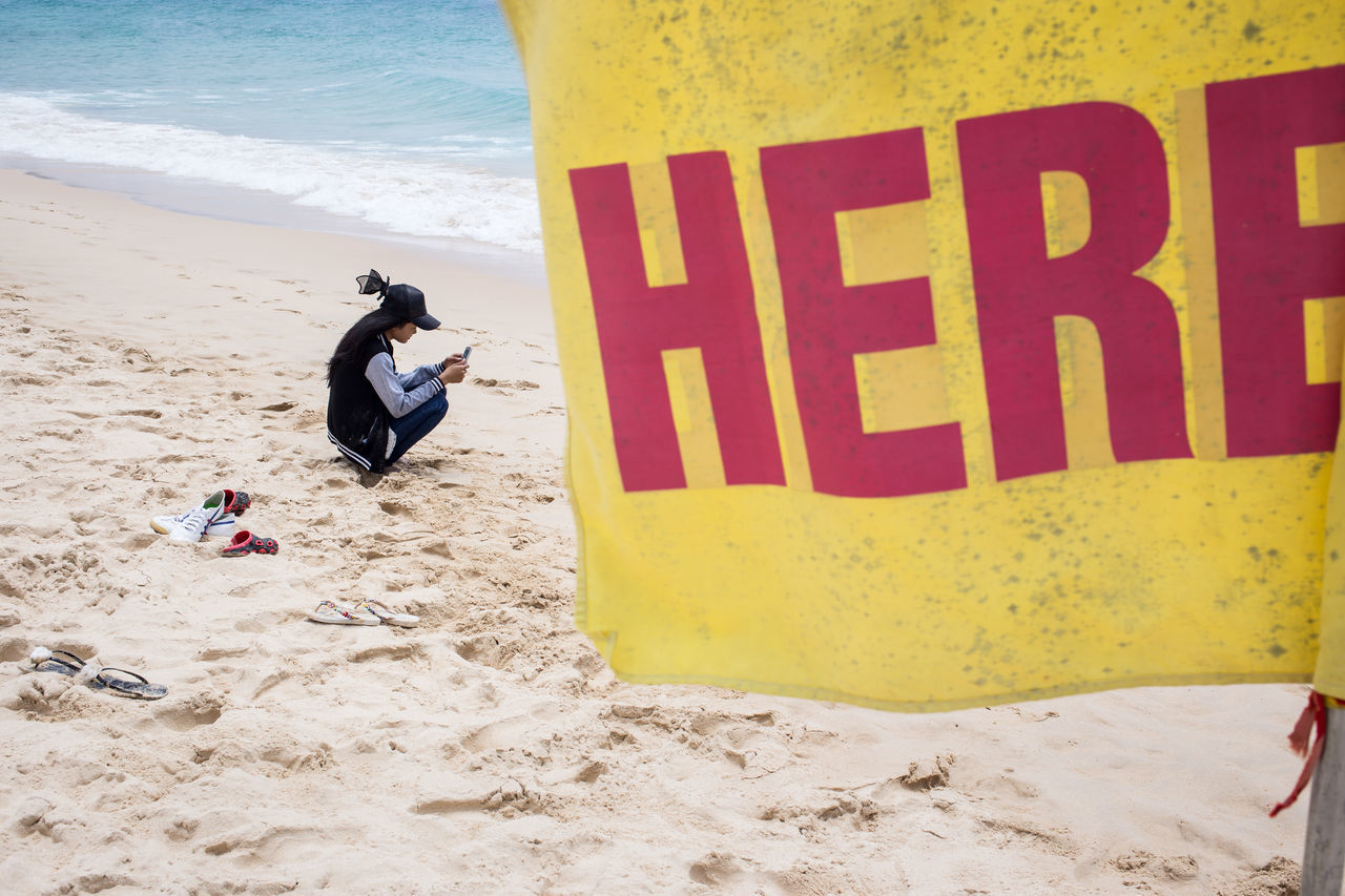 MAN WITH TEXT ON BEACH