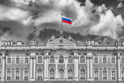 Low angle view of flags in city against cloudy sky