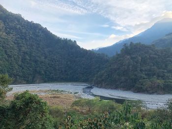 Scenic view of river by mountains against sky