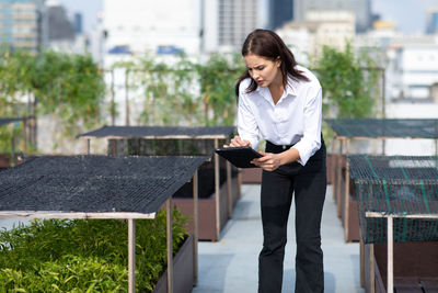 Young woman looking at camera while standing against buildings