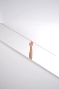 Cropped hand waving against white wall