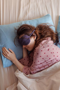 High angle view of girl sleeping on bed at home