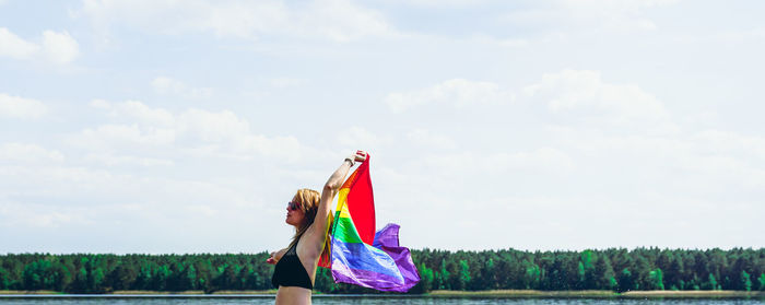 Young woman with rainbow pride flag with lots of sky