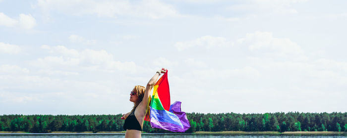 Woman with umbrella on field against sky