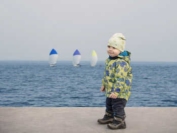 Full length of cute boy in sea against sky