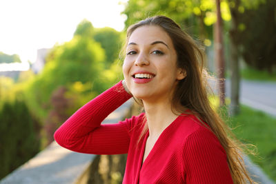 Portrait of smiling young woman standing on footpath