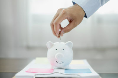 Midsection of man putting coin in piggy bank