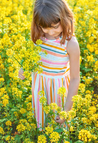 Young woman standing amidst yellow flowering plants