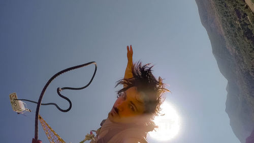 Low angle portrait of young woman against sky