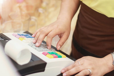 Midsection of woman using cash register in store