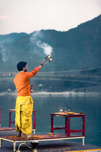 Rear view of man working in boat against sky