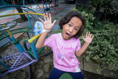 Portrait of cute girl playing with push scooter against plants