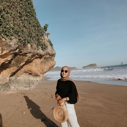 Full length of man on rock at beach against sky