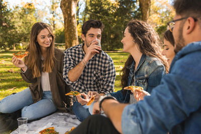 Smiling friends eating food in picnic at park