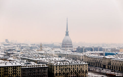 Frozen cityscape against sky during sunset