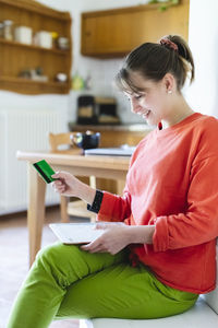 Woman with credit card doing home shopping through digital tablet at home