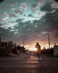 Road by city against sky during sunset