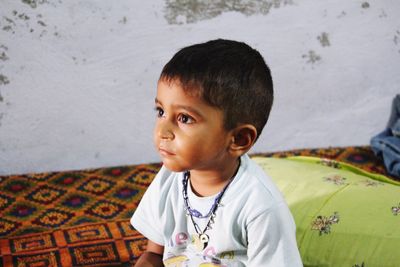 Innocent boy sitting on bed at home