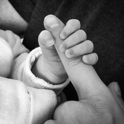 Cropped image of child holding father hand at home