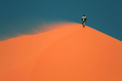 Full length of man on orange sand dune