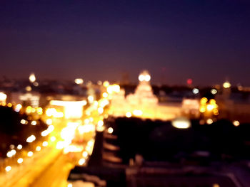 Defocused image of illuminated city against sky at night