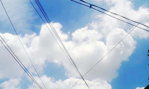 Low angle view of power lines against cloudy sky