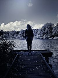 Rear view of woman standing on railing against sky