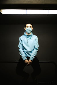 Portrait of young man sitting on wall