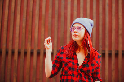 Portrait of beautiful young woman standing against red wall