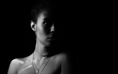 Portrait of shirtless woman against black background