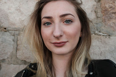 Close-up portrait of young woman smiling against wall