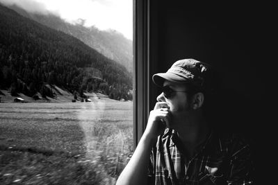 Portrait of young man looking away against window