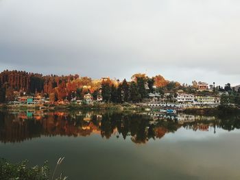 Reflection of buildings and trees in lake against sky