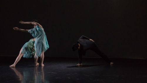Side view of people dancing against black background