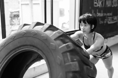 Young woman exercising with tire at home