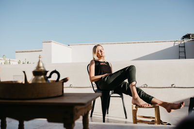 Woman sitting on chair against clear sky