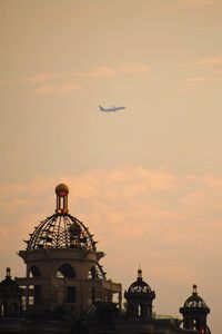 Low angle view of airplane flying against sky during sunset